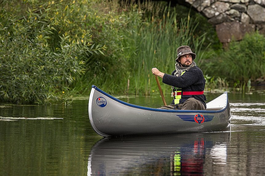 Dieses Bild zeigt einen Mann rudernd im Kanu auf einem Fluss.