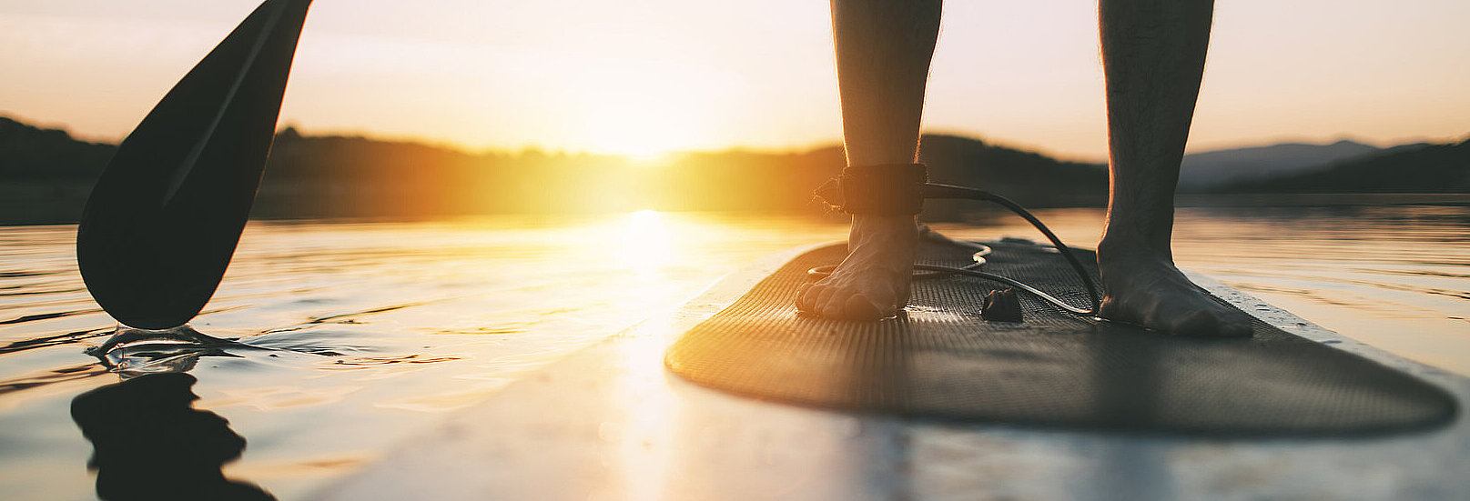 Eine Person steht auf einem Stand-up Paddling Board