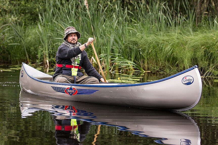 Dieses Bild zeigt einen Mann rudernd im Kanu von der Seite.