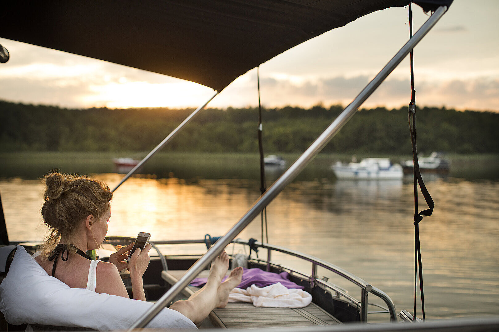 Eine Person sitzt auf einer unserer Yachten auf einem See in der Abendsonne