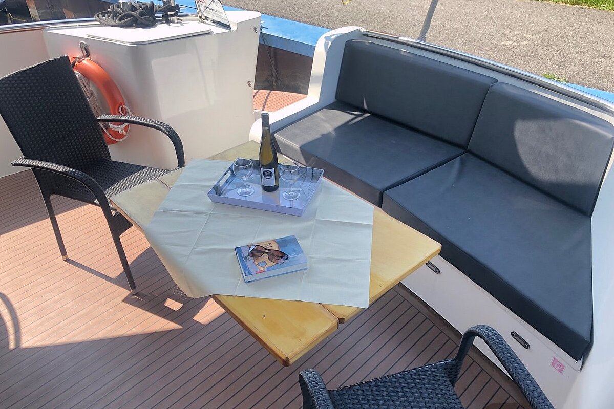 Dieses Bild zeigt unsere Yacht Aquamarin - M-Cruiser 125 - Oberdeck Sitzbank mit Tisch und Stühlen
