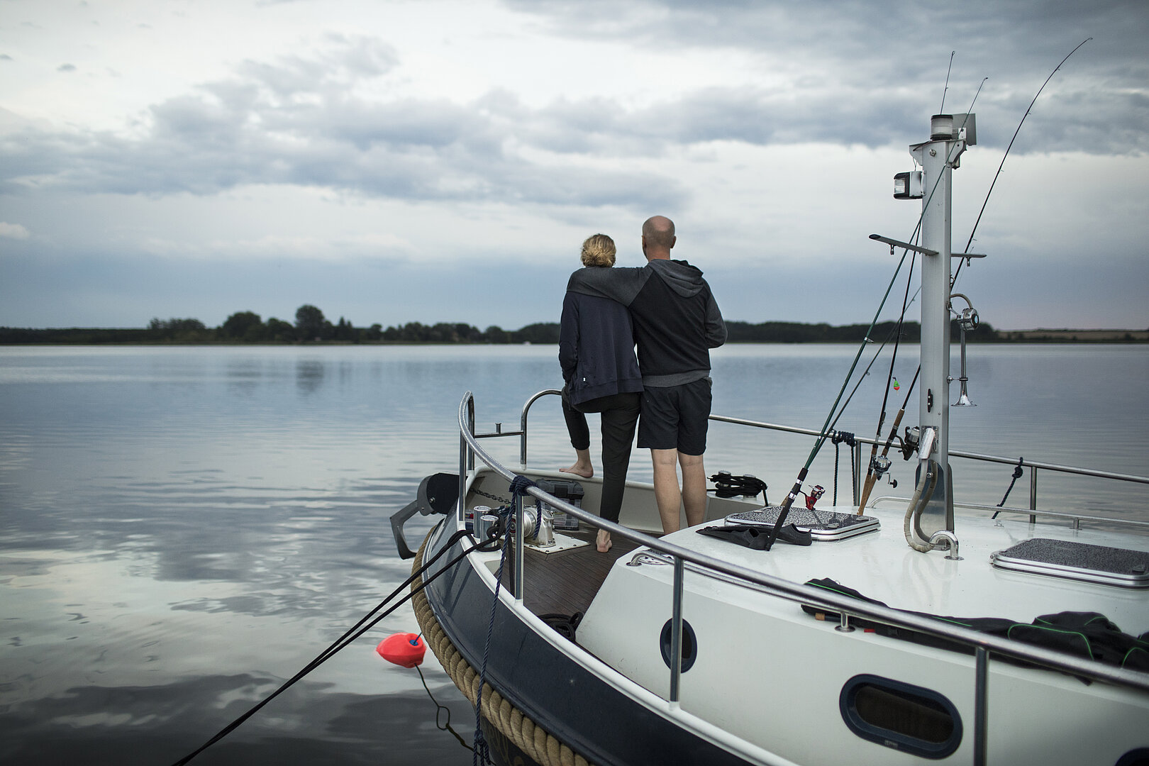 Auf diesem Bild sehen sie zwei Personen auf einer Yacht stehen auf einen See blickend